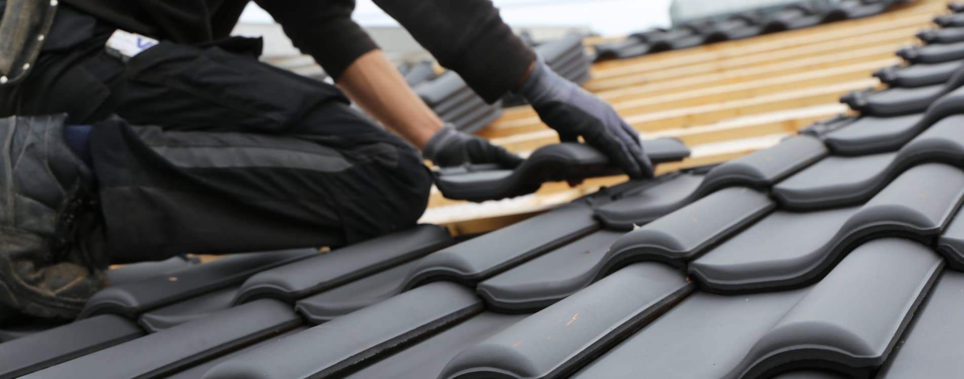Handwerker bei der Eindeckung eines Steildaches mit schwarzen Dachpfannen Dachdecker Reinbek